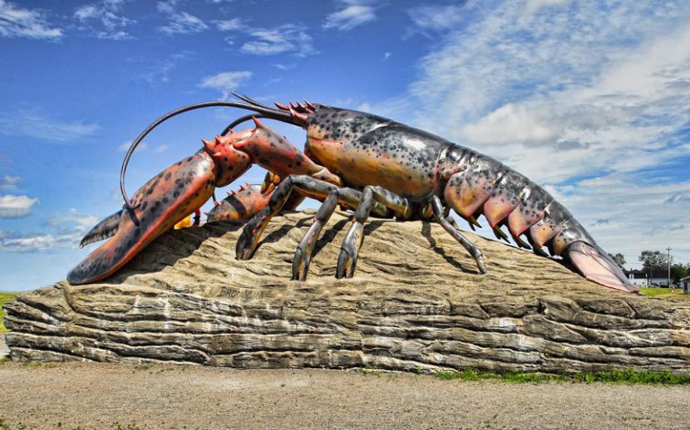 Sculpture de homard sur un rocher, sous un ciel bleu