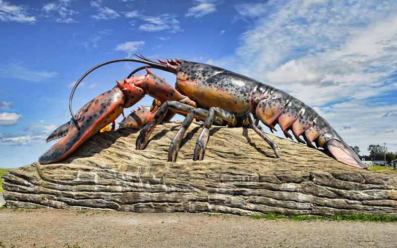 Sculpture de homard sur un rocher, sous un ciel bleu