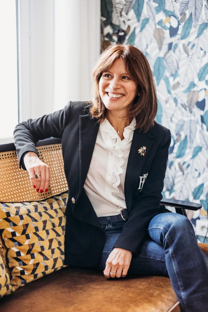 Katya Corbineau souriante, assise de trois quarts sur un canapé