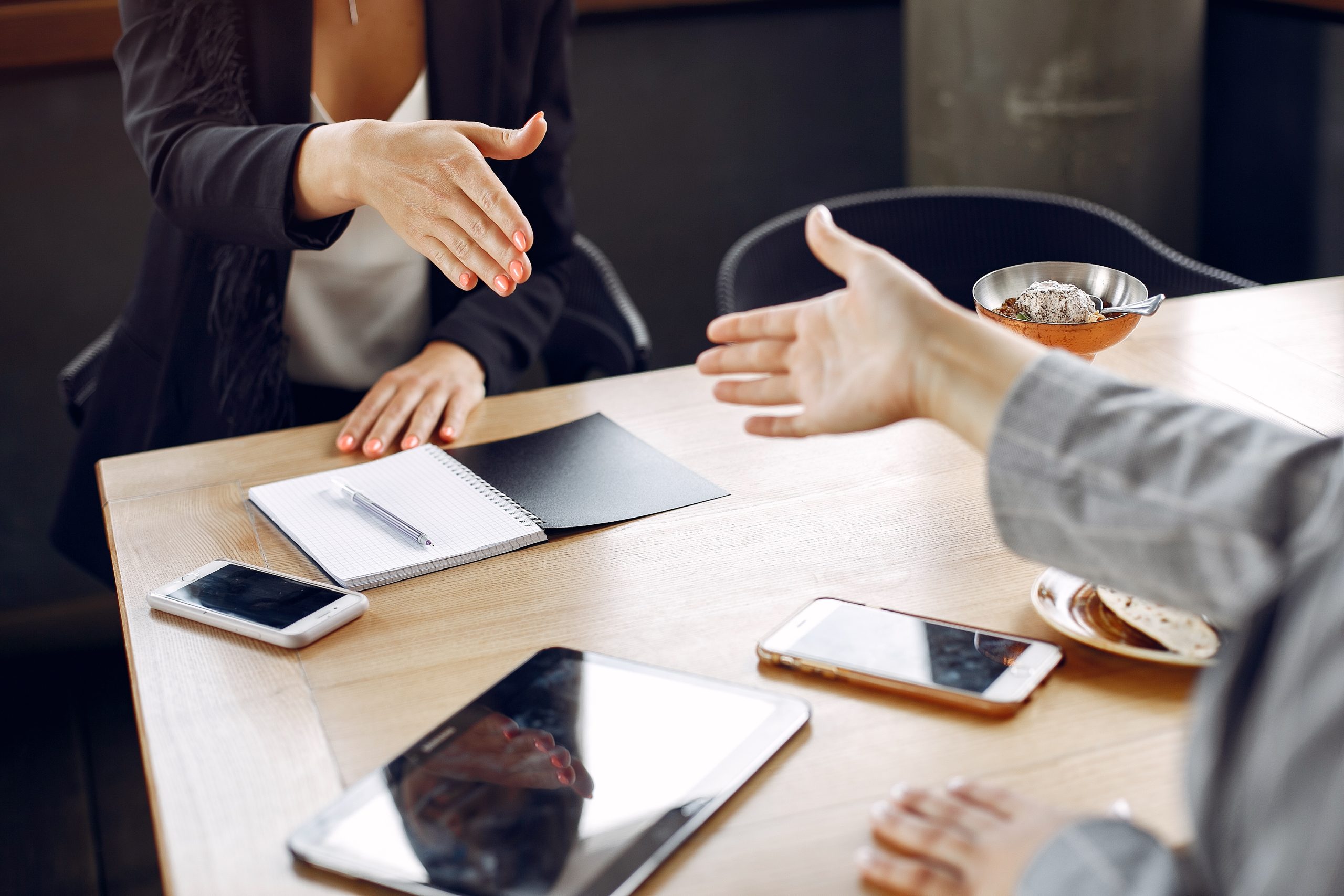 Deux personnes se tendent la main au-dessus d’une table.